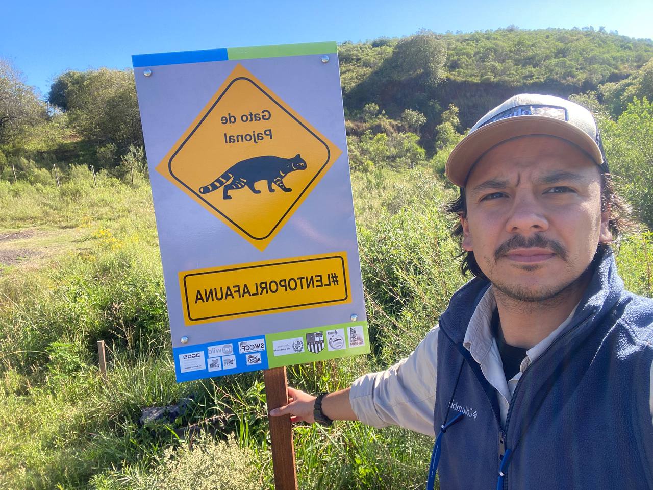 Conservationist beside a Pampas cat road safety sign in the field